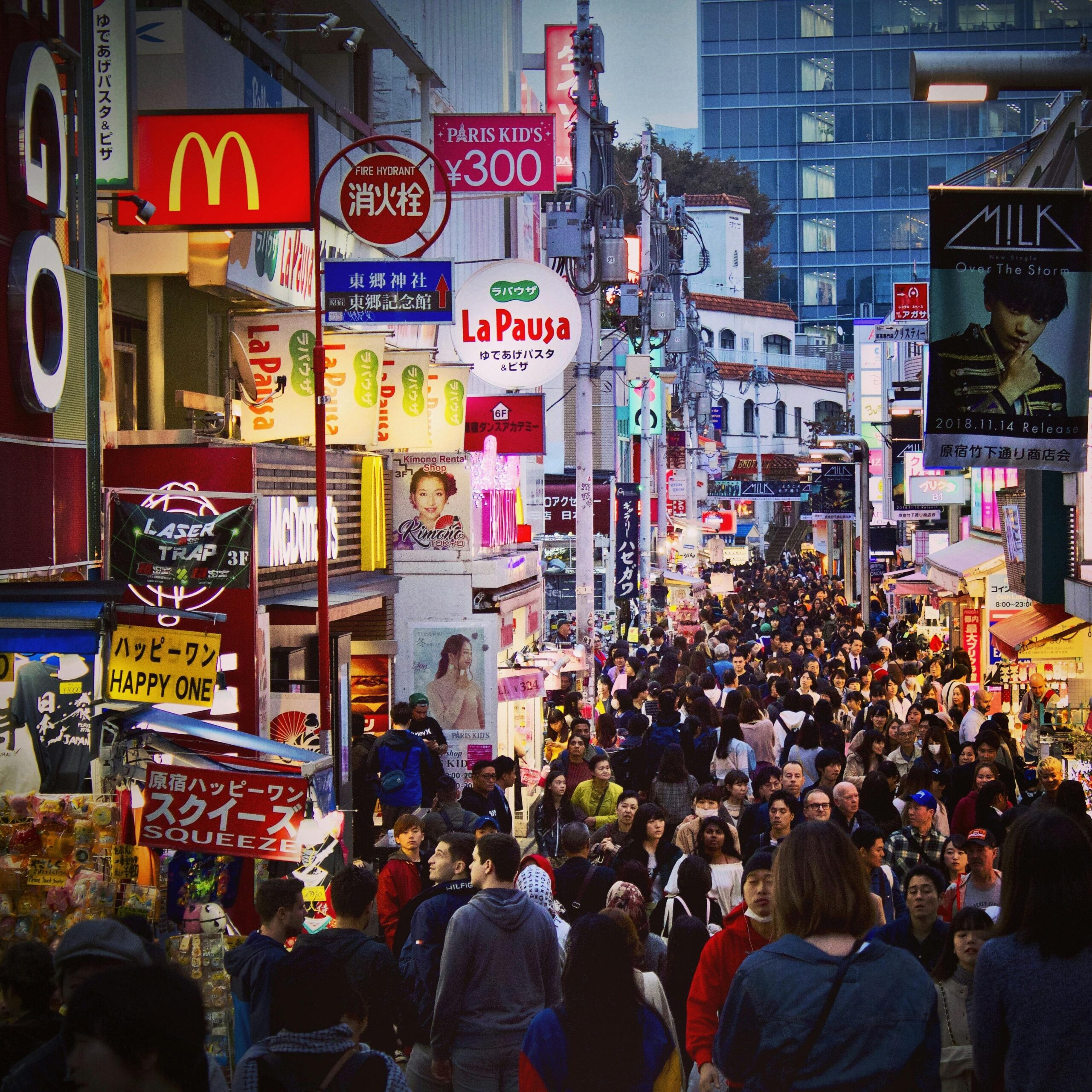 Crowded Takeshita Street in Tokyo filled with vibrant shops and signage during twilight.